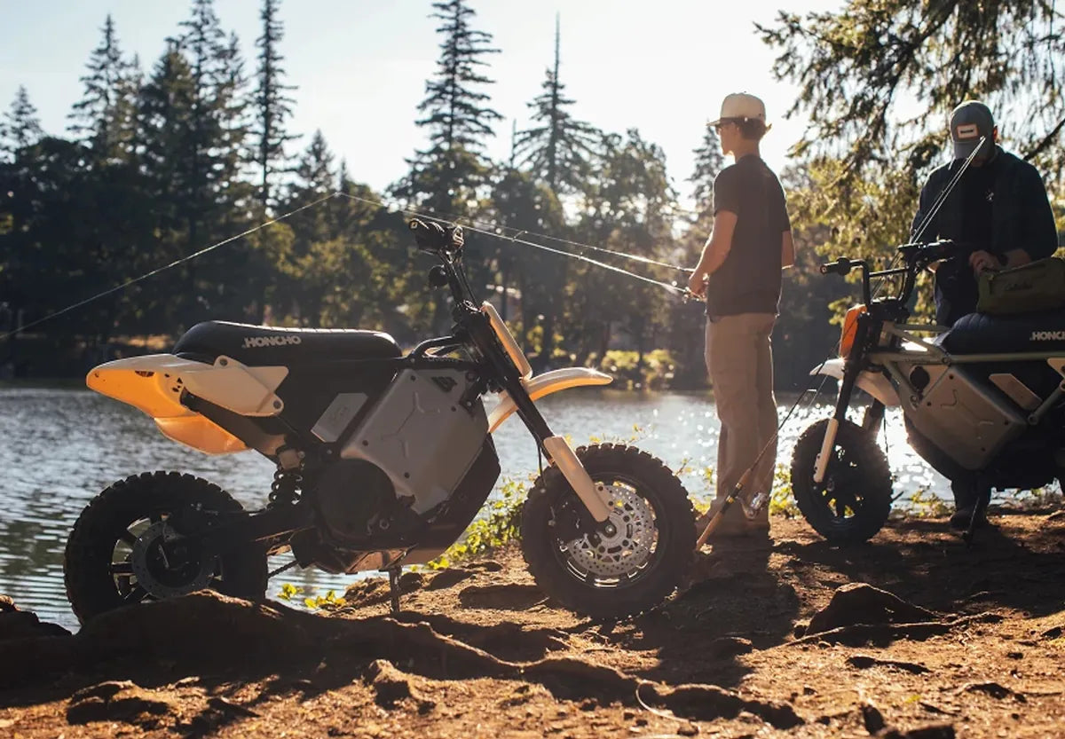 Two LiveWire S4 Honcho Trail motorcycles and riders beside a wooded river